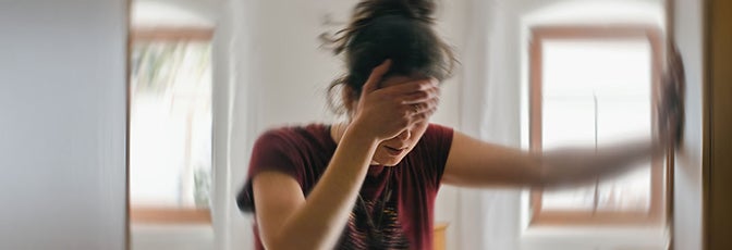 Osoba trzyma głowę w pomieszczeniu